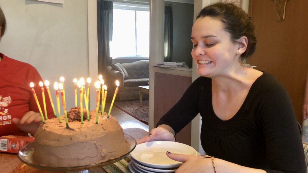 A person sitting at a table with a birthday cake

Description automatically generated