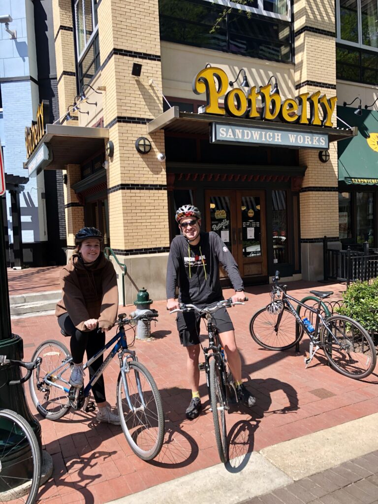 A person riding a bicycle in front of a building

Description automatically generated